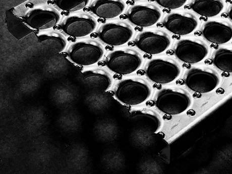 O-grip safety grating with debossed holes and perforated buttons for slip-resistance.